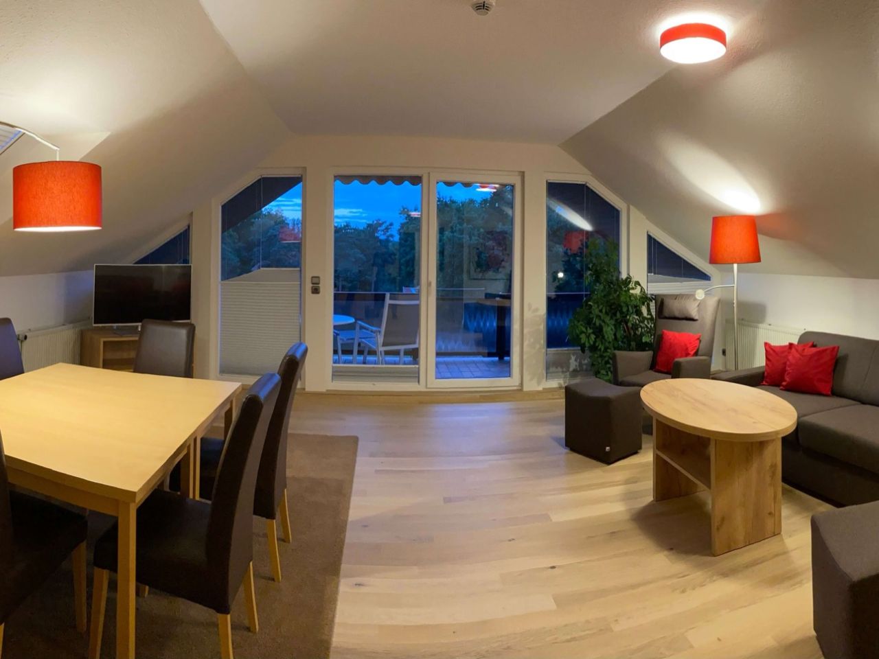 Große Suite mit großen Balkonfenstern, Tisch, Sofa und Stehlampfen in einem modern eingerichten Zimmer